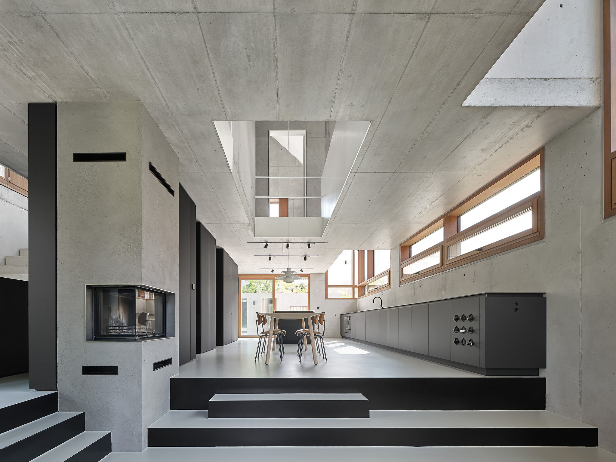 Architektonischer Wohn- und Essbereich aus Sichtbeton mit maßgefertigter dunkler Küchenzeile von Hildinger und Koch